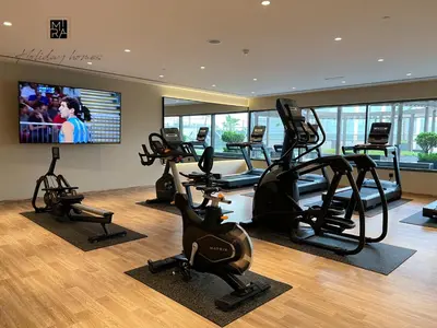 a gym with treadmills and ellipticals and a flat screen tv at Mira Holiday Homes - Serviced apartment in Downtown in Dubai