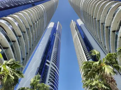 two tall buildings with palm trees in the middle at Cosmos Living 1 Bedroom Paramount Hotels in Dubai