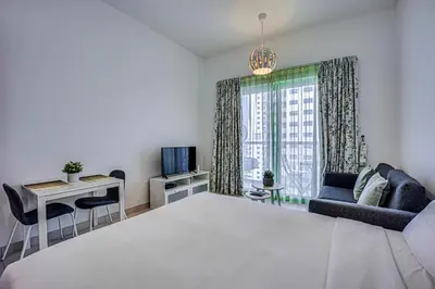 a bedroom with a large white bed and a table and chairs at Canal View apartment in Marina in Dubai