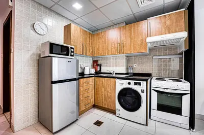 a kitchen with wooden cabinets and a washer and dryer at Canal View apartment in Marina in Dubai