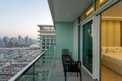 a balcony with two chairs and a bed and a city at Sunrise Bay 2, Emaar Beachfront - Mint Stay in Dubai