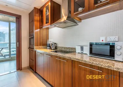 a kitchen with wooden cabinets and a microwave at 2 Bed Room in Attessa Tower, Dubai Marina by Desert City Stays in Dubai