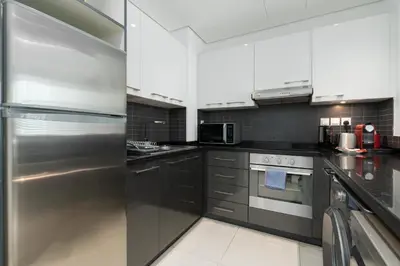 a kitchen with white cabinets and a stainless steel refrigerator at Vacay Lettings - Silverene Marina Retreat - Waterfront Apartment Steps from Marina Mall in Dubai