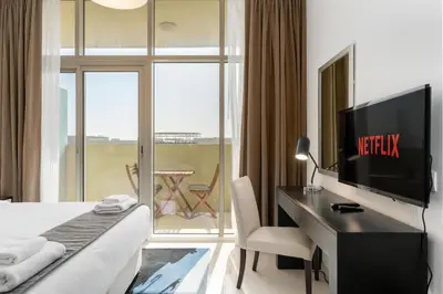 a hotel room with a bed and a desk with a television at Vacay lettings - Upgraded studio at Damac tower JVC in Dubai
