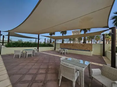 a patio with tables and chairs under a large umbrella at Vacay lettings - Upgraded studio at Damac tower JVC in Dubai