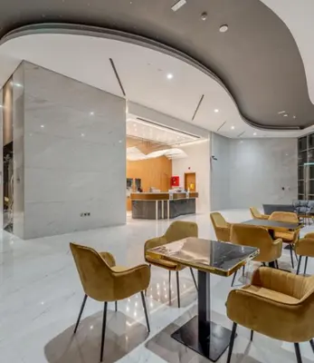 a lobby with tables and chairs and a kitchen at Elegant 2BR view with rooftop pool The Bay in Dubai