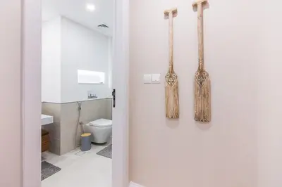 a white bathroom with a toilet and a door at Burj Al Arab View - 1BR in MJL Lamtara 1- Burj Al Arab View 703 in Dubai