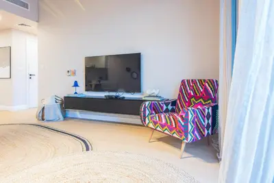 a living room with a chair and a television at Burj Al Arab View - 1BR in MJL Lamtara 1- Burj Al Arab View 703 in Dubai