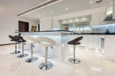 a kitchen with three bar stools in front of a counter at Tiara Residence Ruby, Palm Jumeirah - Mint Stay in Dubai