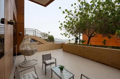 a balcony with chairs and tables and a staircase at Tiara Beach Residences, Palm Jumeirah Dubai - Mint Stay in Dubai