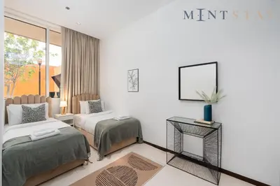 a bedroom with two beds and a table and a mirror at Tiara Beach Residences, Palm Jumeirah Dubai - Mint Stay in Dubai