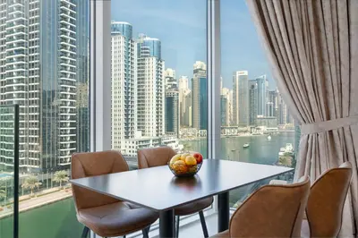 a table and chairs in a room with a large window at Vacay Lettings - Waterfront Luxury home with full Marina view in Dubai