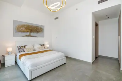 a white bedroom with a bed and a painting on the wall at Vacay Lettings - Waterfront Luxury home with full Marina view in Dubai