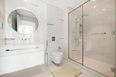 a white bathroom with a shower and a toilet at Free Beach Access! Beautiful Palm Jumeirah & Dubai Eye in Dubai