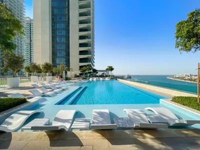 a swimming pool with white lounge chairs next to the ocean at Free Beach Access! Beautiful Palm Jumeirah & Dubai Eye in Dubai