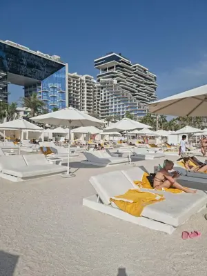 a man laying on beds on a beach with umbrellas at FIVE Palm Jumeirah 2BR Luxury Penthouse, Private Pool, Full Marina Sea View in Dubai