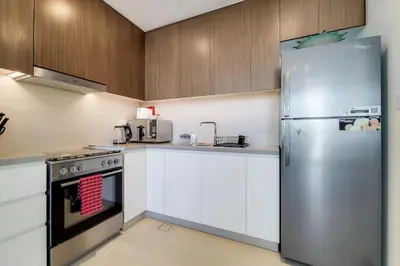 a kitchen with a stainless steel refrigerator and white cabinets at 5242 Tower 2 - Light One Bedroom in Dubai