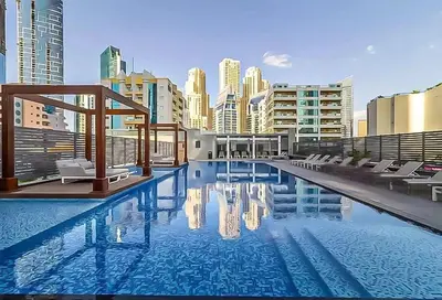 a large swimming pool with chairs and a city at Stylish Apartment Balcony and Sea Views in Dubai