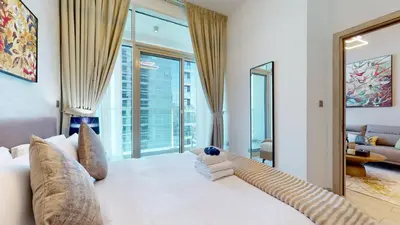 a bedroom with a white bed with a large window at Stylish Apartment Balcony and Sea Views in Dubai