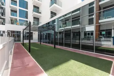a building with a green lawn in front of it at Perfect 2br for families in JVC in Dubai