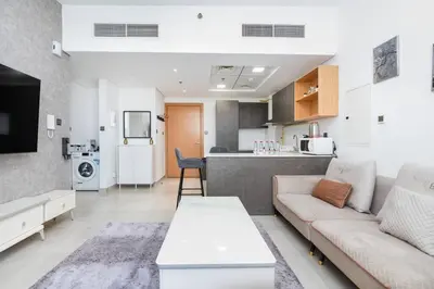 a living room with a couch and a kitchen at Perfect 2br for families in JVC in Dubai
