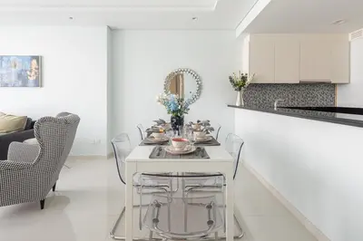 a white kitchen with a white table and chairs at Frank Porter - Paramount Midtown in Dubai