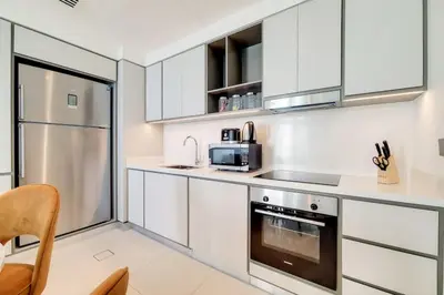 a kitchen with white cabinets and a stainless steel refrigerator at Sunrise Bay 2 - Chic Two Bedroom in Dubai