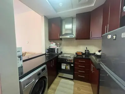 a kitchen with wooden cabinets and a stove top oven at Stylish Studio in Discovery Garden MED100 in Dubai