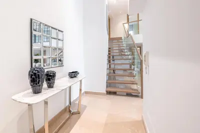 a white hallway with a staircase and a table with vases on it at Ultra Luxury JBR Duplex Penthouse - Free 5 star beach access in Dubai