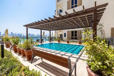 an outdoor swimming pool with a pergola and a wooden bench at 2BR Le Pont B3 Full Sea and Pool View in Dubai