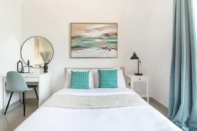 a white bedroom with a bed and a desk at Frank Porter - Lakeside Tower D in Dubai