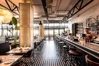 a restaurant with a long bar with tables and chairs at Ultra Luxe 5BR Al Bateen I Private Beach and Pool I JBR Full Sea View Beachfront in Dubai