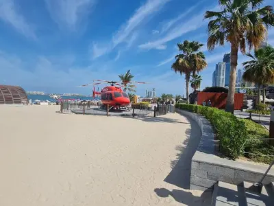 a red helicopter parked on a beach with palm trees at Ultra Luxe 5BR Al Bateen I Private Beach and Pool I JBR Full Sea View Beachfront in Dubai