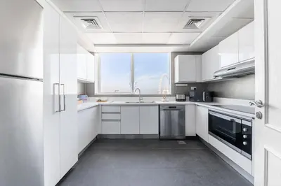 a white kitchen with a sink and a window at Ultra Luxe 5BR Al Bateen I Private Beach and Pool I JBR Full Sea View Beachfront in Dubai