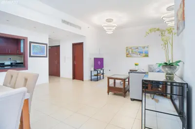 a living room with a table and a dining room at JBR - Apartment plus maid in Dubai