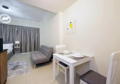 a small living room with a table and a chair at RH- Voguish, Studio in Downtown, short walk to Burj Khalifa in Dubai