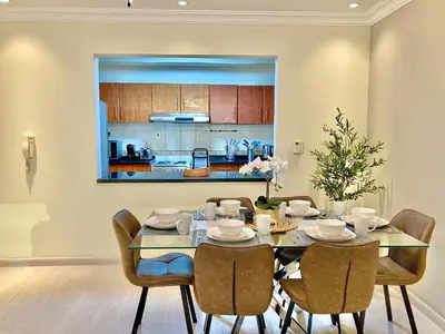 a dining room with a table and chairs and a kitchen at White Sage - Lakefront Apartment Amidst Parks With Lake Access in Dubai