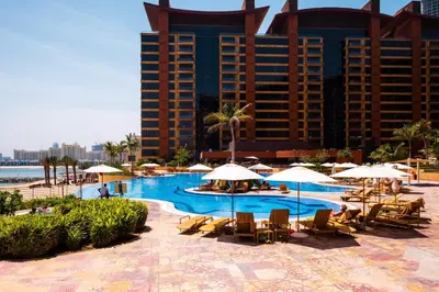 a pool with chairs and umbrellas in front of a hotel at Tiara Residences, Palm Jumeirah Dubai - Mint Stay in Dubai