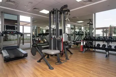 a gym with treadmills and machines in a room at Everluxe Azizi Montrell Lovely Studio in Dubai