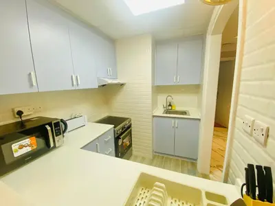 a kitchen with white cabinets and a sink at Manchester Regency - 2BR Apartment in Dubai Marina in Dubai