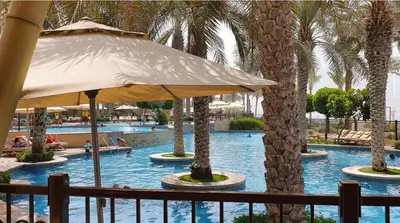 a swimming pool with palm trees and an umbrella at Luton Vacation Homes - Luxury & Spacious 1BR North Residence Fairmont , Palm Jumeirah - 90AB3 in Dubai