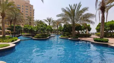 a swimming pool with palm trees in a resort at Luton Vacation Homes - Luxury & Spacious 1BR North Residence Fairmont , Palm Jumeirah - 90AB3 in Dubai