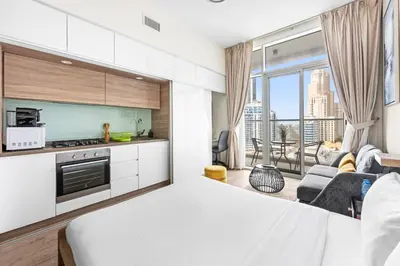 a white bedroom with a kitchen and a living room at ALiving Cozy Studio with Canal View I Studio One, Dubai Marina in Dubai