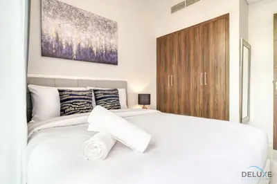 a bedroom with a white bed and a wooden cabinet at Alluring 3BR Townhouse at DAMAC Hills 2, Dubailand by Deluxe Holiday Homes in Dubai
