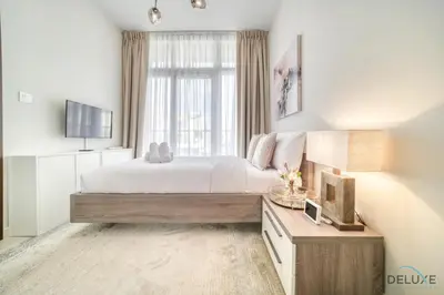 a bedroom with a large bed and a television at Alluring 3BR Townhouse at DAMAC Hills 2, Dubailand by Deluxe Holiday Homes in Dubai
