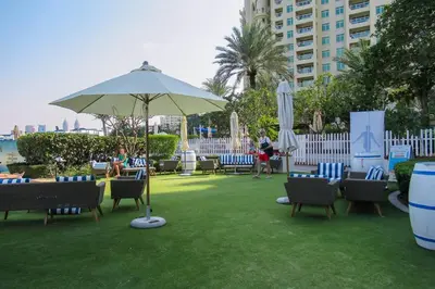 a patio with chairs and an umbrella on the grass at Frank Porter - Al Nabat in Dubai