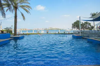 a large swimming pool with palm trees and the ocean at Frank Porter - Al Nabat in Dubai