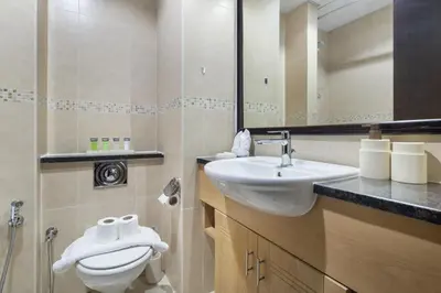 a bathroom with a sink and a toilet and a mirror at Chic JLT Studio, Lake View, Pool, Metro Access in Dubai
