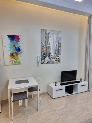 a living room with a table and a tv at Premium Lovely Studio with Balcony in Dubai in Dubai