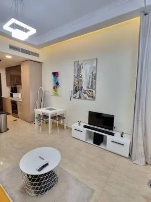 a living room with a tv and a table at Premium Lovely Studio with Balcony in Dubai in Dubai